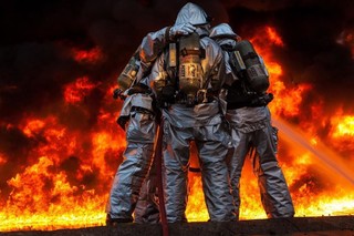 橘红消防写实大火中抱团的消防员背景图片